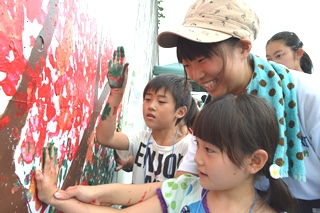 小学生に塗り方を教える関野さんの写真
