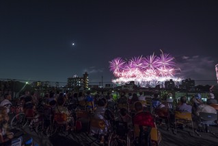 車いす観覧スペースから見える花火大会のクライマックスの写真