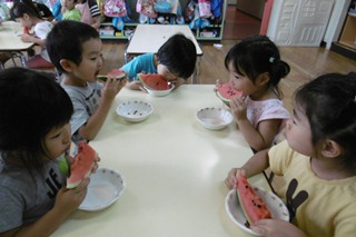 おやつにスイカを食べる子どもたちの写真