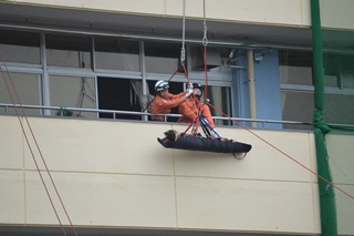 ロープを使用して高所にいる逃げ遅れた被災者を救助する訓練の写真