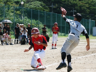 塁に向かって走る選手と、その前にボールを取ろうとする選手の写真