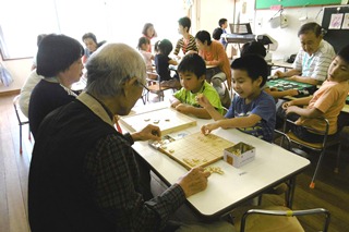 おじいちゃんと将棋をする子どもの写真