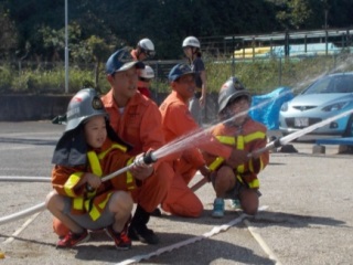 消防服を着て放水体験をする子どもたちの写真