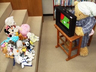 くま館長に紙芝居を読んでもらうぬいぐるみたちの写真