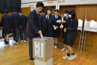 実際の選挙で使う投票箱に投票用紙を入れる生徒の写真
