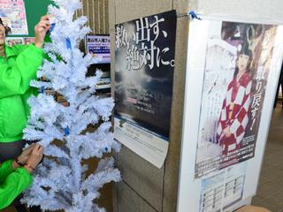 白いクリスマスツリーにリボンを結ぶ様子の写真