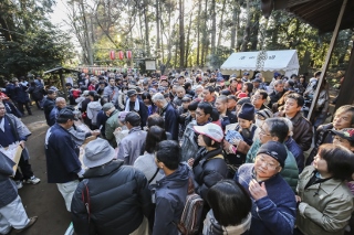 ふるまわれた紅白餅とみかんを受け取る大勢の観客の写真