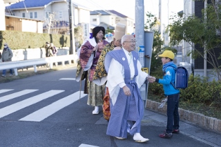 「送り込み」の時に小学生と握手をする宇佐見会長の写真