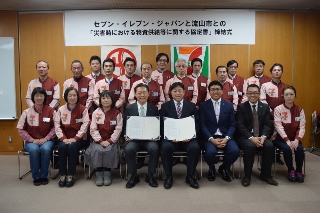 市長、内竹さん、協定式に参加した市内セブンイレブンの店長さんたちの写真