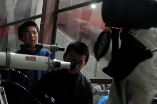 子どもが望遠鏡をのぞきこんでいる写真