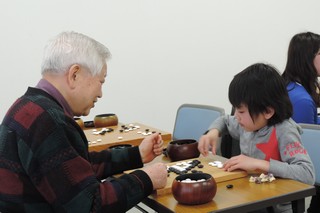 子どもがおじいさんと碁を打っている写真