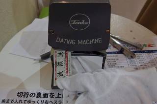 硬券切符型の入場券にダッチングマシンで日付を印刷している様子の写真