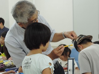 子どもに切り絵を見せる飯田さんの写真