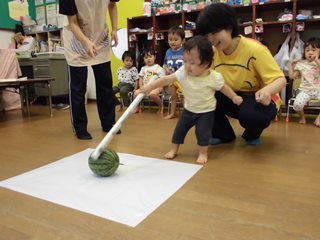 スイカに棒を当てる子どもの写真