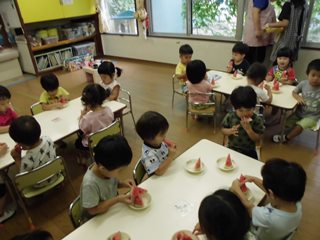 おやつにスイカを食べる子どもたちの写真