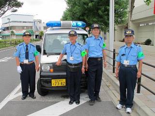 青色回転灯車両の前での集合写真