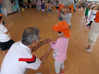 竹とんぼの飛ばし方を教えてもらう子どもの写真