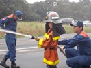 消防士の服で放水体験をする男の子の写真