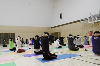 ヨガマットに座り、体をほぐす参加者の写真