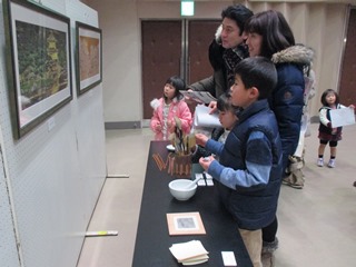 画材や道具を見ながら後藤純男氏の絵を鑑賞する親子の写真