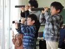 作成した天体望遠鏡をのぞく子どもたちの写真