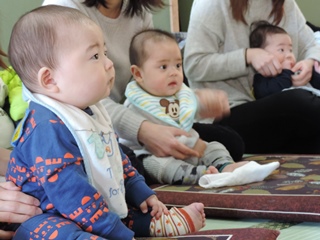 ママに抱かれて前を見つめる赤ちゃんの写真