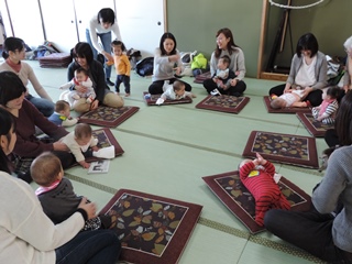 輪になって赤ちゃんをあやしながら談笑するママたちの写真