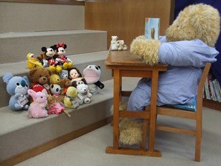 くま館長に読み聞かせをしてもらうぬいぐるみたちの写真