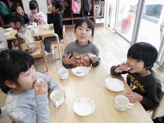 紅白まんじゅうをほおばる子どもたちの写真