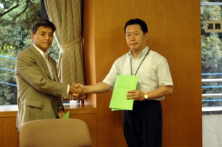 コアラテレビの岡村雅宣代表取締役社長と井崎市長が固い握手を