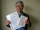 本と賞状を手にする恵良さんの写真