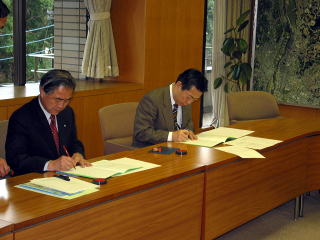 協定書に署名する服部信濃町長と井崎流山市長の写真