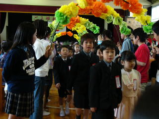 花のアーチをくぐる新1年生の写真