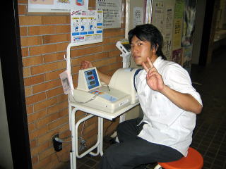血圧を測る男子学生の写真