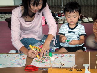 なかよく紙とんぼをつくる親子の写真